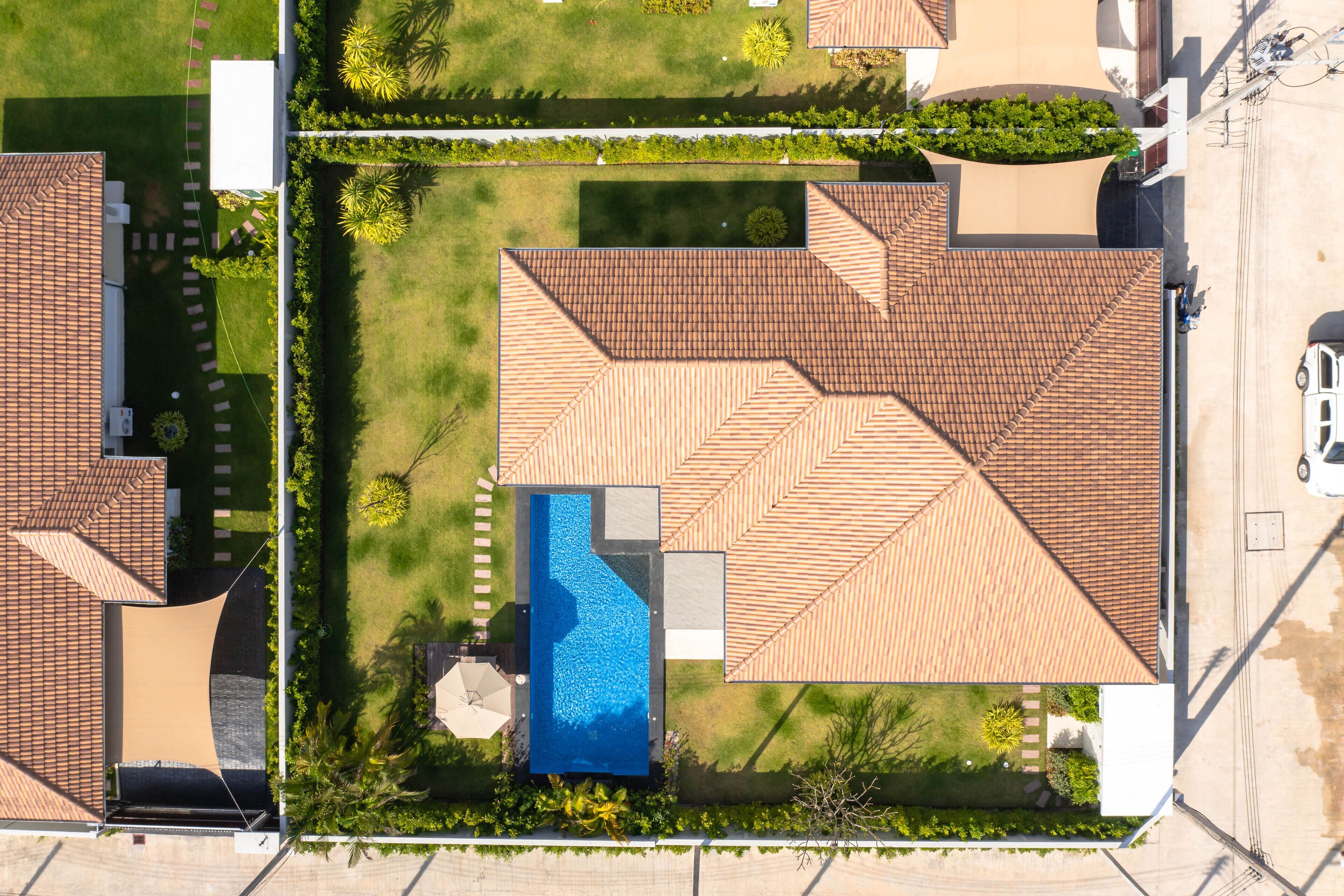 Vista aérea de una zona residencial con varias casas, una piscina y jardines bien cuidados.