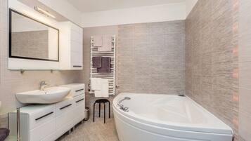 A modern bathroom with a freestanding bathtub, a large mirror, and a vanity with a sink and drawers.