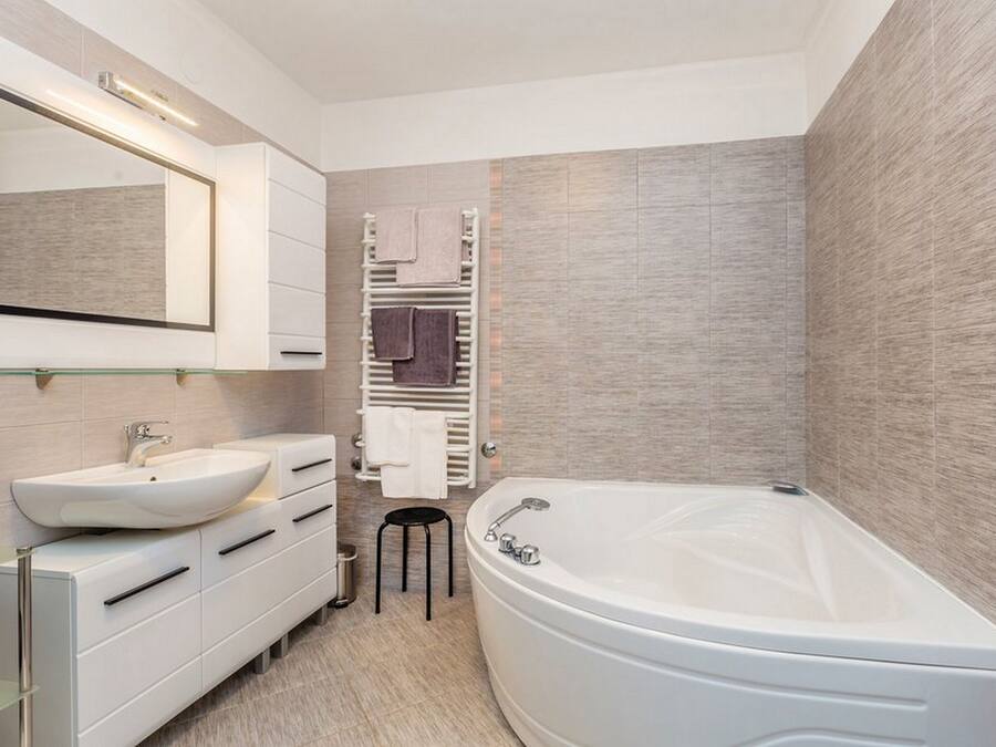Ein modernes Badezimmer mit einer freistehenden Badewanne, einem großen Spiegel und einem Waschtisch mit Spüle und Schubladen.