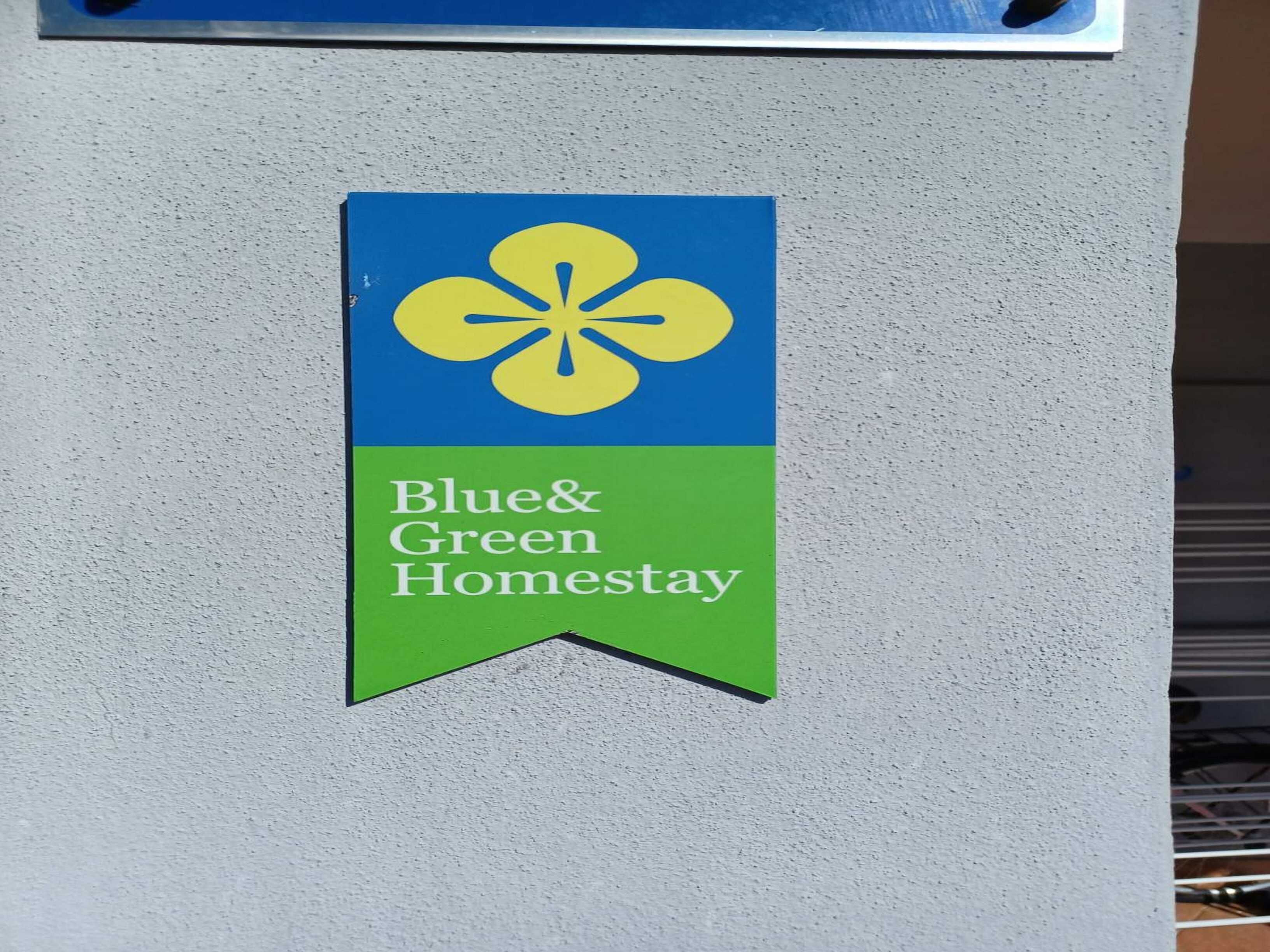 A Blue & Green Homesstay sign on a wall.
