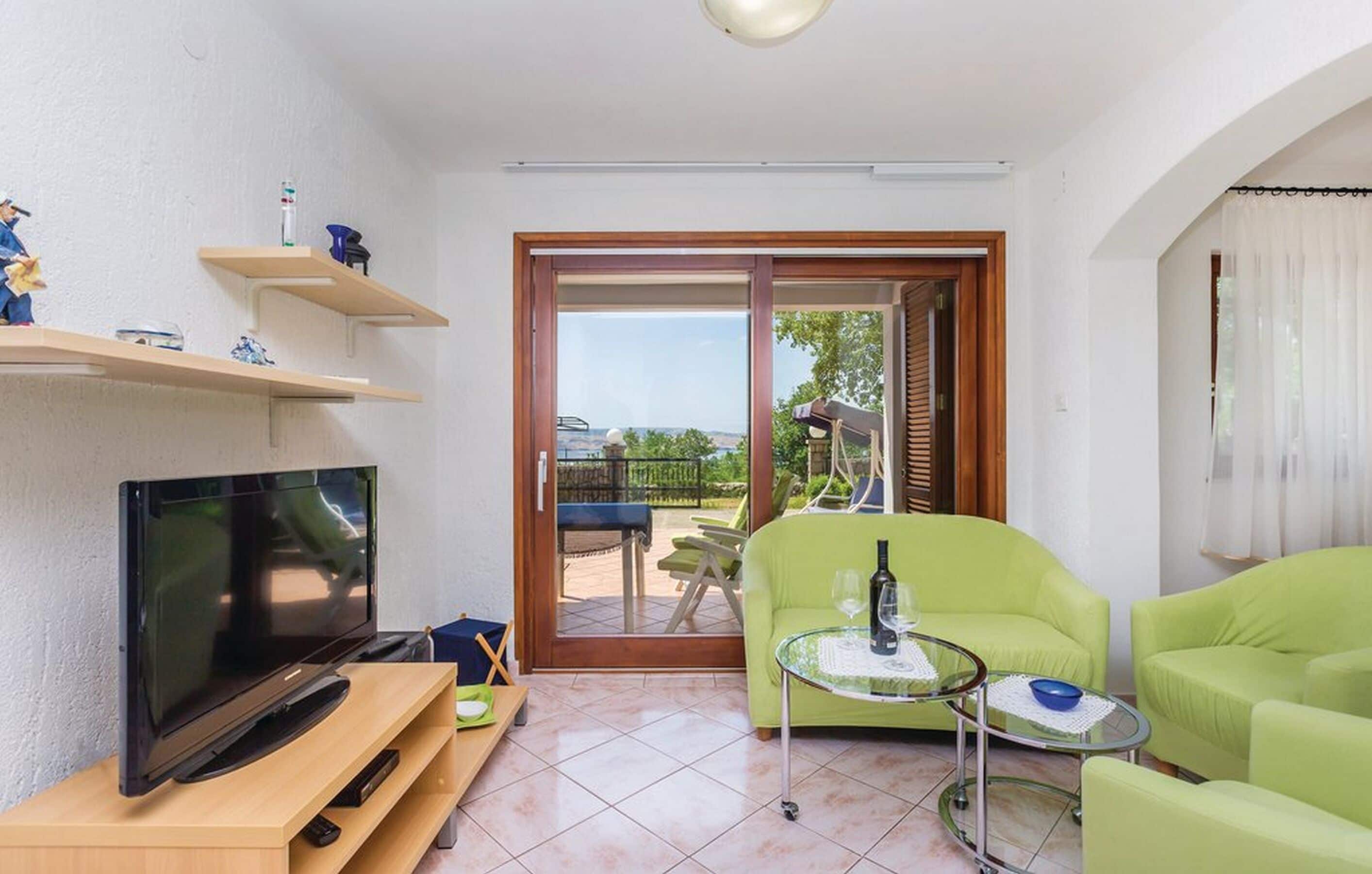 A living room with a TV, green sofas, a glass coffee table, and a sliding glass door leading to an outdoor area.