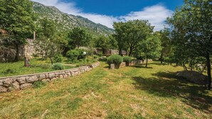 A stone wall, a grassy area, and trees. - Apartments Paola (Karlobag)