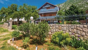 A two-story building with a stone wall and a garden in front. - Apartments Paola (Karlobag)