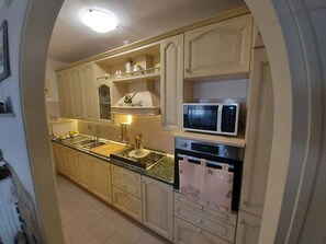 Una cucina con mobili in legno, un lavello, un forno a microonde e una lavastoviglie.