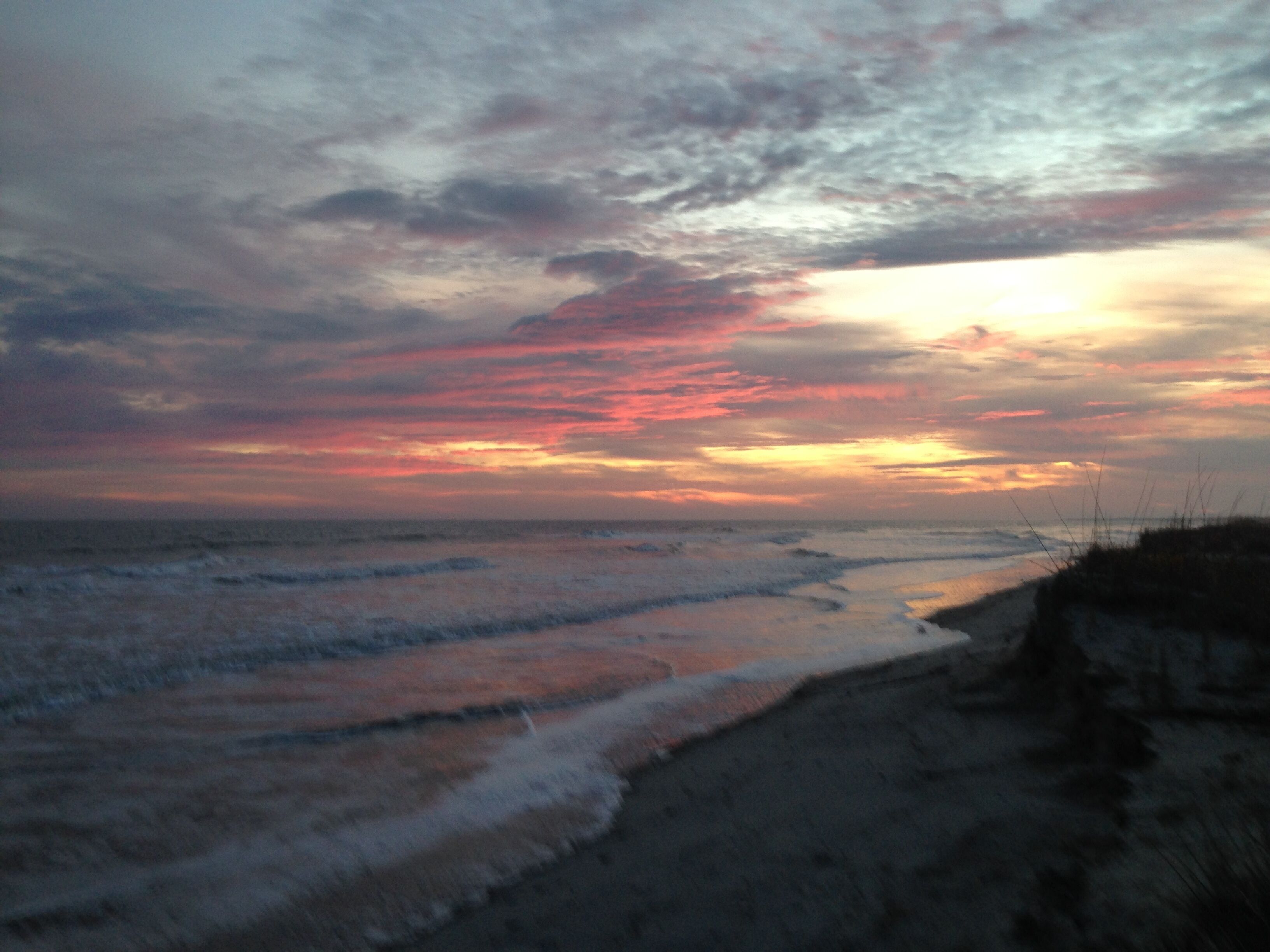 A beach with waves and a sunset.