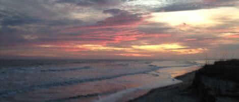 A beach with waves and a sunset.