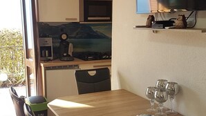 Eine moderne Küche mit Essbereich, einem Flachbildfernseher und Blick ins Freie.