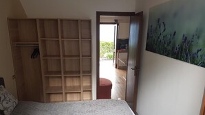 Ein Schlafzimmer mit einem Bett, einem Holzschrank, einem roten Sessel und einem Bild an der Wand.