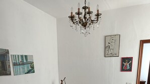 Ein Wohnzimmer mit einem gemusterten Sofa, einem gemusterten Sessel, einer Chandelierleuchte und Kunstwerken an den Wänden.