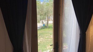 Una puerta que da a un jardín con un árbol y un contenedor azul.