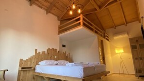 Una habitación con estructura de madera, una cama, una mesita y una lámpara.