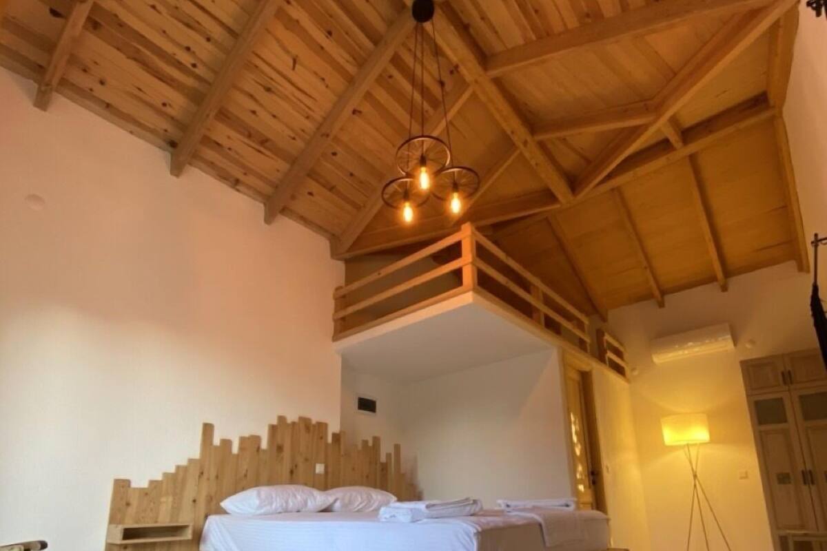 A wooden-framed room with a bed, a small table, and a lamp.
