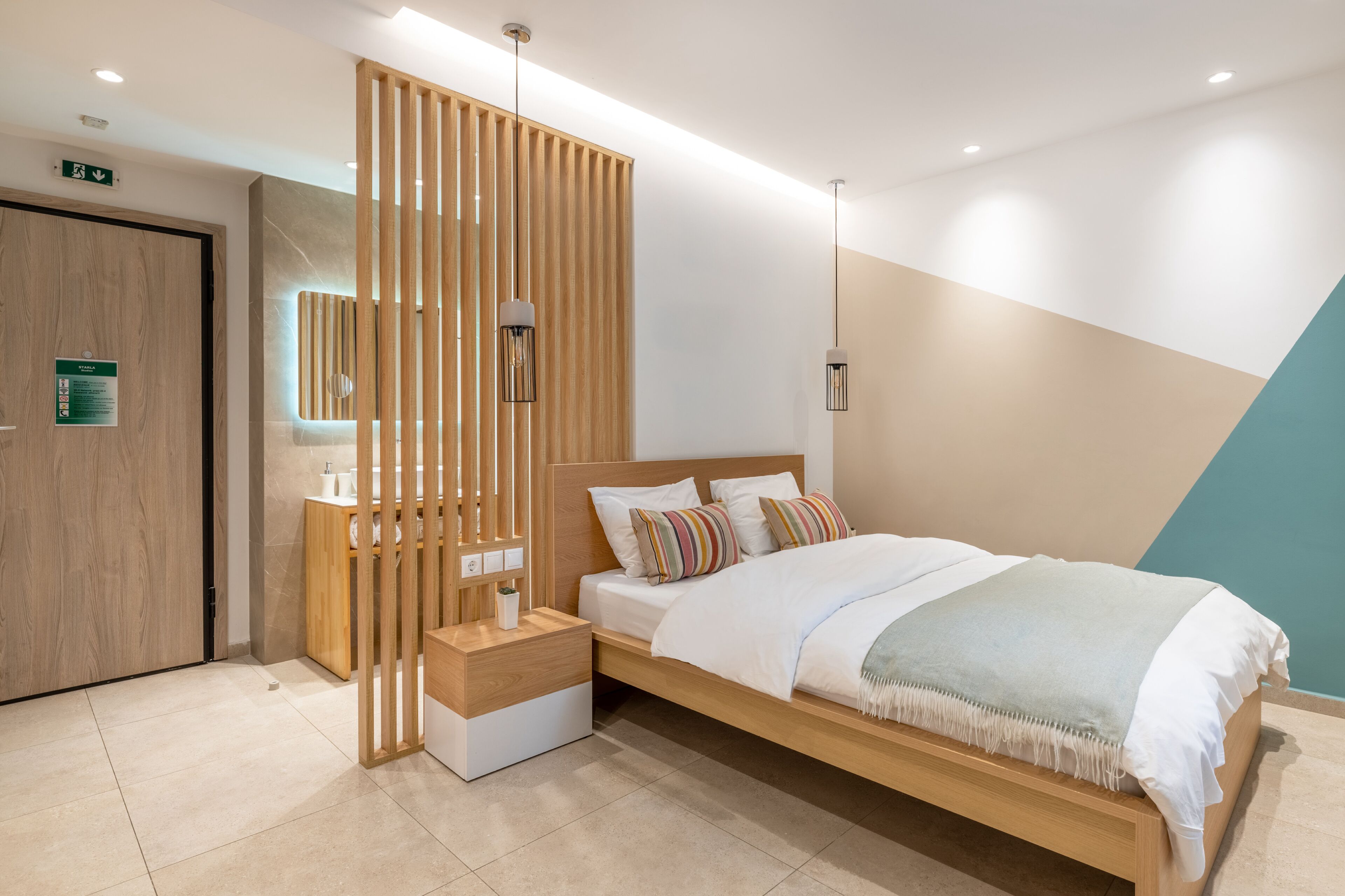 A modern bedroom with a wooden bed, bedside tables, a nightstand, a large mirror, and a wooden partition.