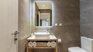 A modern bathroom with a white sink, a mirror, and a toilet. - Starla Studios (Athens)