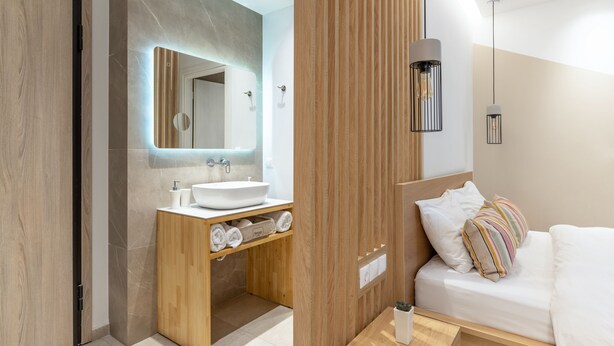 A modern bathroom with a wooden vanity, a large mirror, and a built-in sink. - Starla Studios (Athens)