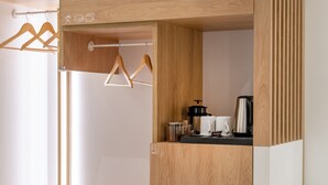 A modern wooden wardrobe with a built-in shelf, a hanging rack, and a small kitchen area with a kettle and cups. - Starla Studios (Athens)