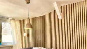 Uma sala de estar moderna com um sofá, uma mesinha, uma luminária pendente e um tapete estampado.