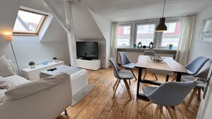 Um loft moderno com área de jantar, sala de estar e TV.