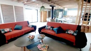 Una sala de estar moderna con dos sofás rojos, una mesa de centro y un comedor al fondo.