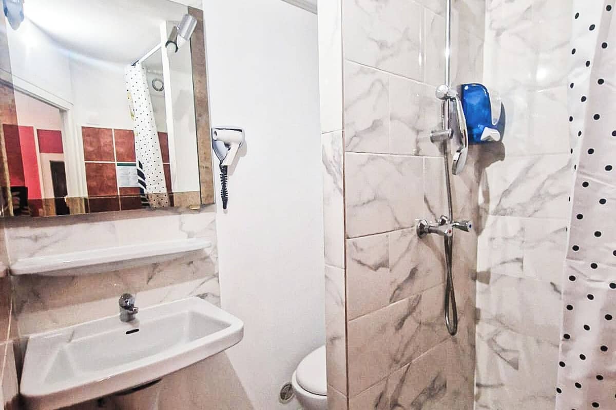 A bathroom with a marble shower, a sink, and a toilet.