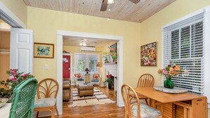 Un comedor con una mesa y sillas de madera, un sofá rojo y un jarrón decorativo con flores.