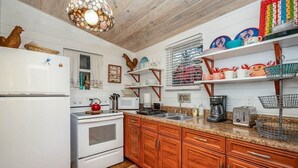 Una cocina con armarios de madera, un refrigerador blanco, una estufa y diversos electrodomésticos.