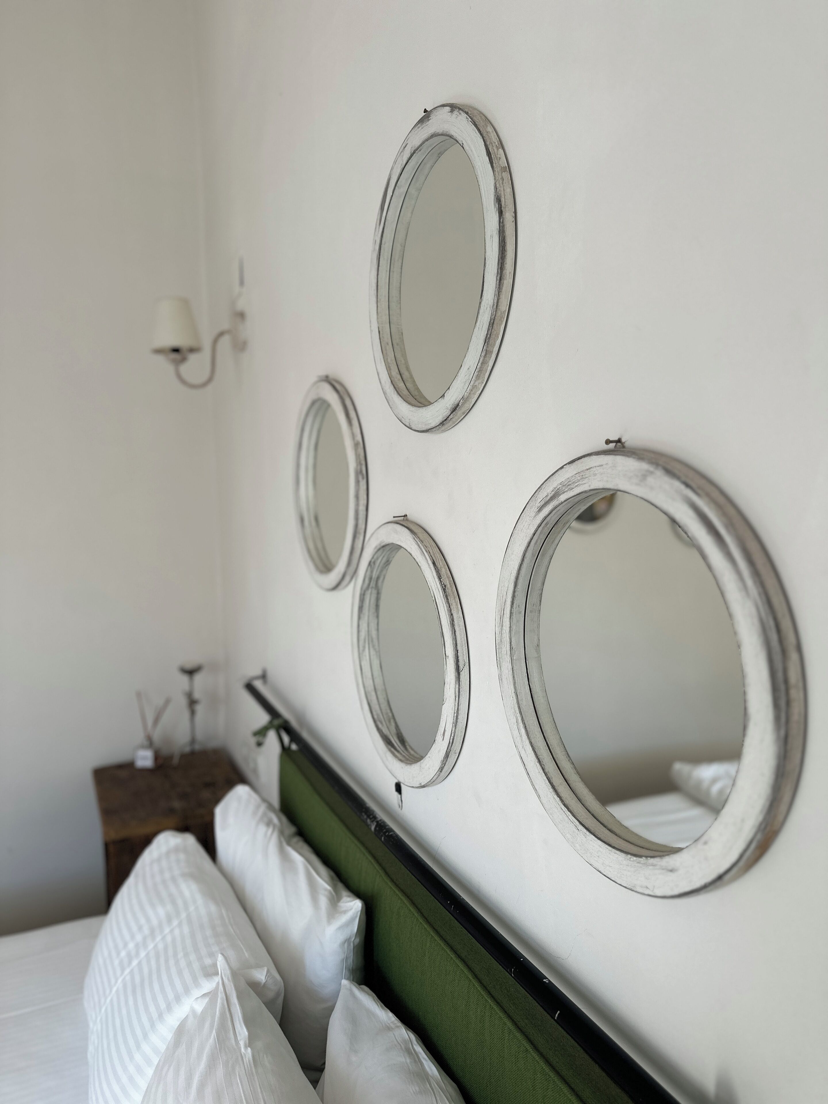 A hotel room with a bed, a nightstand, and four wall-mounted mirrors.