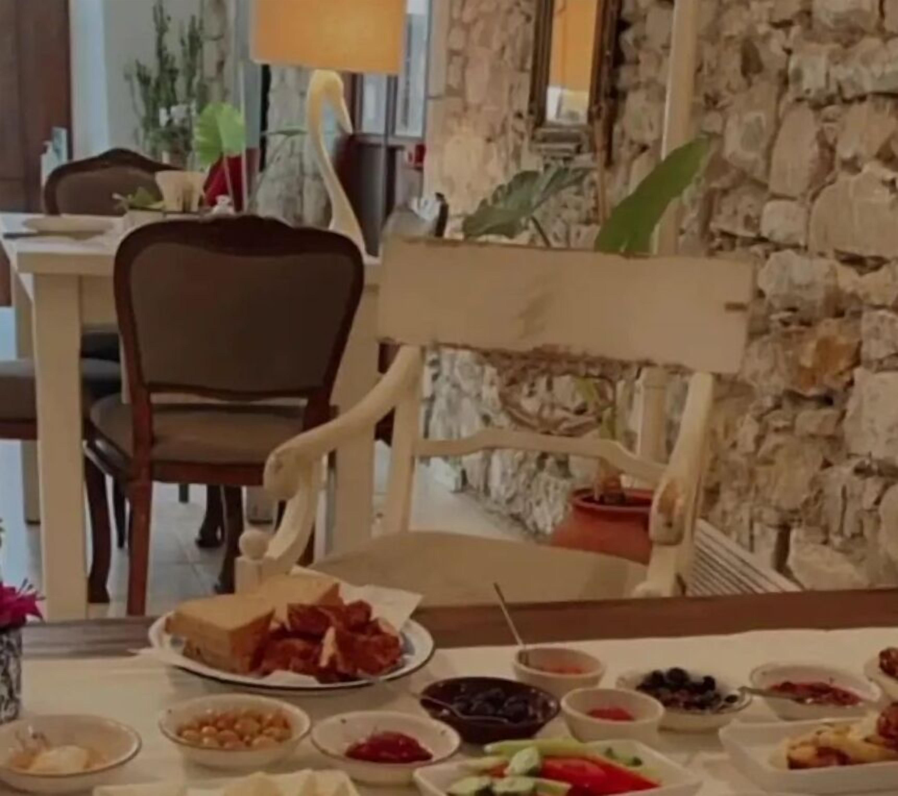 A dining table with various dishes, a chair, and a stone wall in the background.