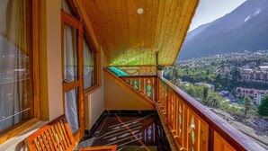 Un balcon avec des balustrades en bois et une vue sur une ville et des montagnes.