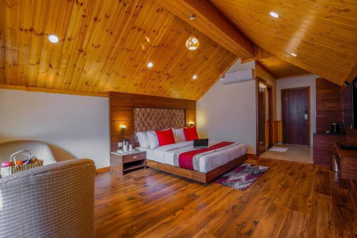 Un dormitorio con techo de madera, una cama con almohadas rojas, una mesita de noche y una silla.