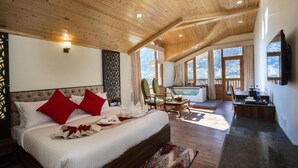Une chambre spacieuse avec un grand lit, un coin salon avec vue et un espace repas séparé.