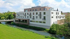 A modern multi-story building with a flat roof, large windows, and balconies. - Hotel VIVO (Schierling)