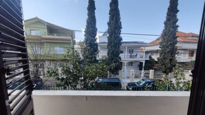 Un balcon donnant sur un quartier résidentiel, avec vue sur les maisons et les voitures garées.