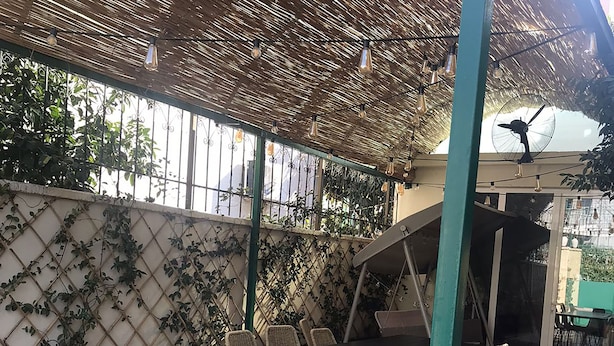 Une terrasse extérieure avec une table et des chaises, un ventilateur et un plafond décoratif.