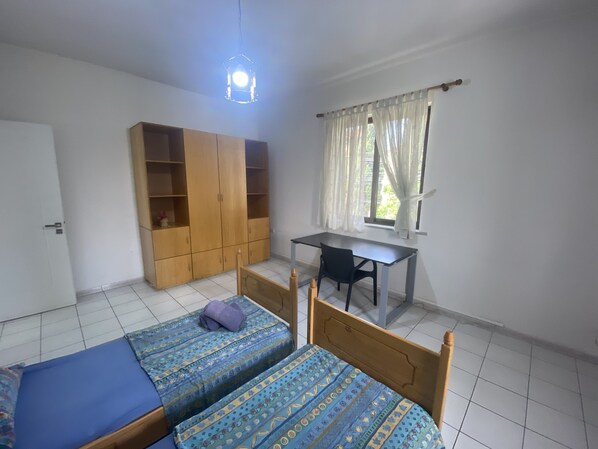 Una habitación con dos camas, un escritorio y un armario.