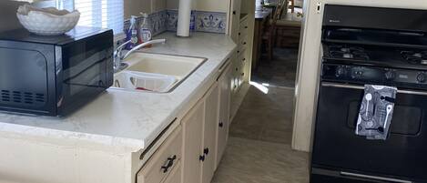 Een koelkast, een microgolfoven, een oven, kookgerei, borden en bestek