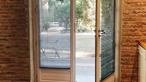 Una habitación con pared de ladrillo, una puerta con panel de vidrio y vista al exterior.