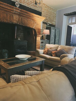 Un salón acogedor con chimenea de ladrillo, un sofá de cuero y una mesa de centro de madera.