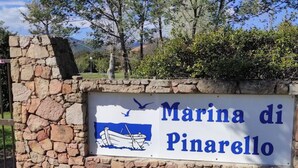 Un muro de piedra con un letrero que dice "Marina di Pinarello" y presenta una ilustración de un barco.