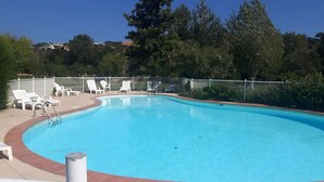 Una piscina con sillas de descanso blancas y una valla de metal.