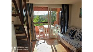 Un balcón con sofá y sillones, una escalera y vistas a zonas verdes.