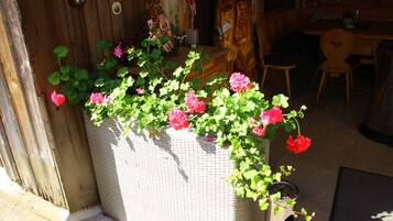 A wicker planter with pink flowers and green foliage.