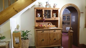 A wooden cabinet with glass doors, a small table with a vase of flowers, and a plant in a woven basket. - Hotel Gasthof Zum weissen Lamm (Hohenberg a.d.Eger)