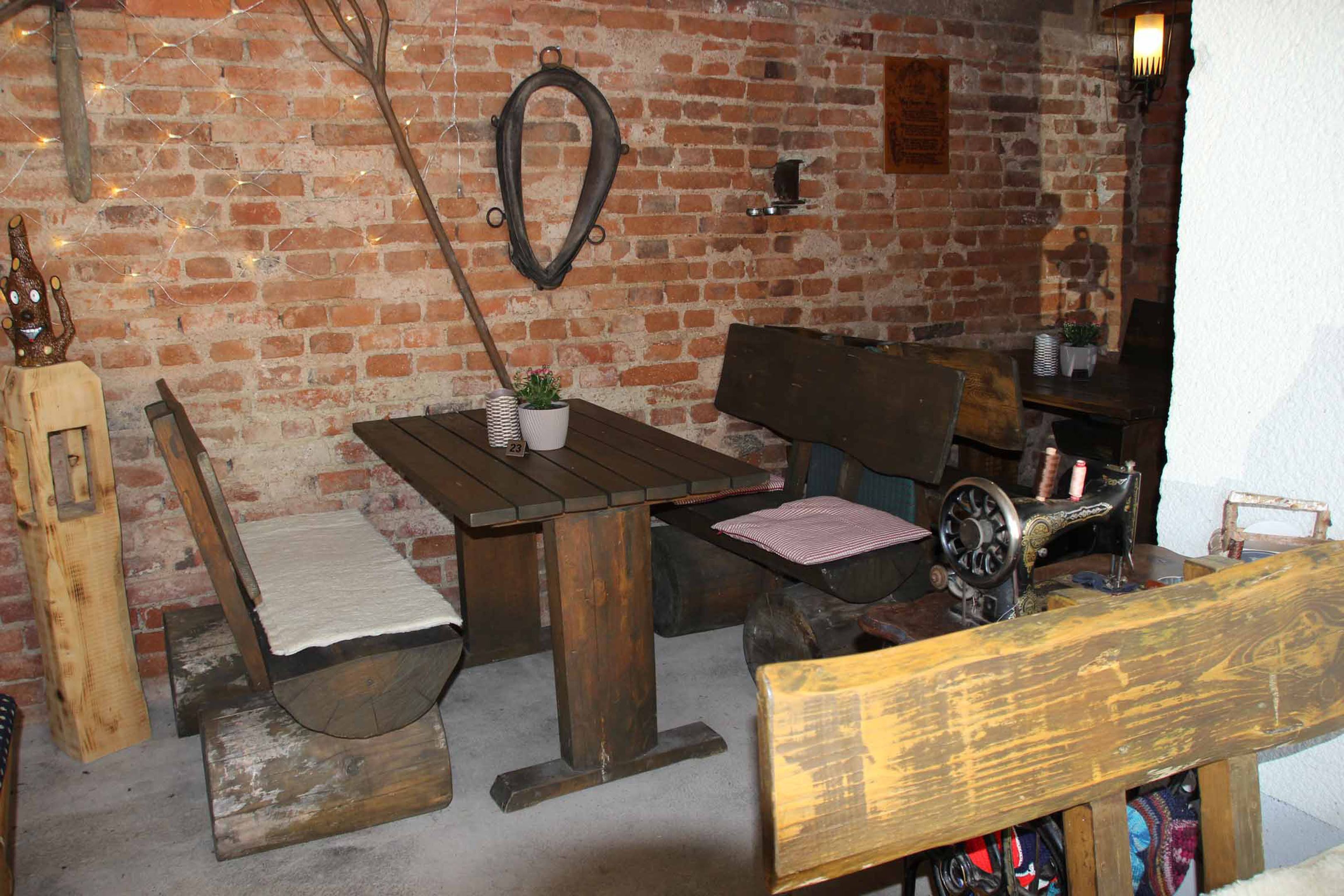 A rustic room with a brick wall, wooden furniture, a sewing machine, and a small plant.