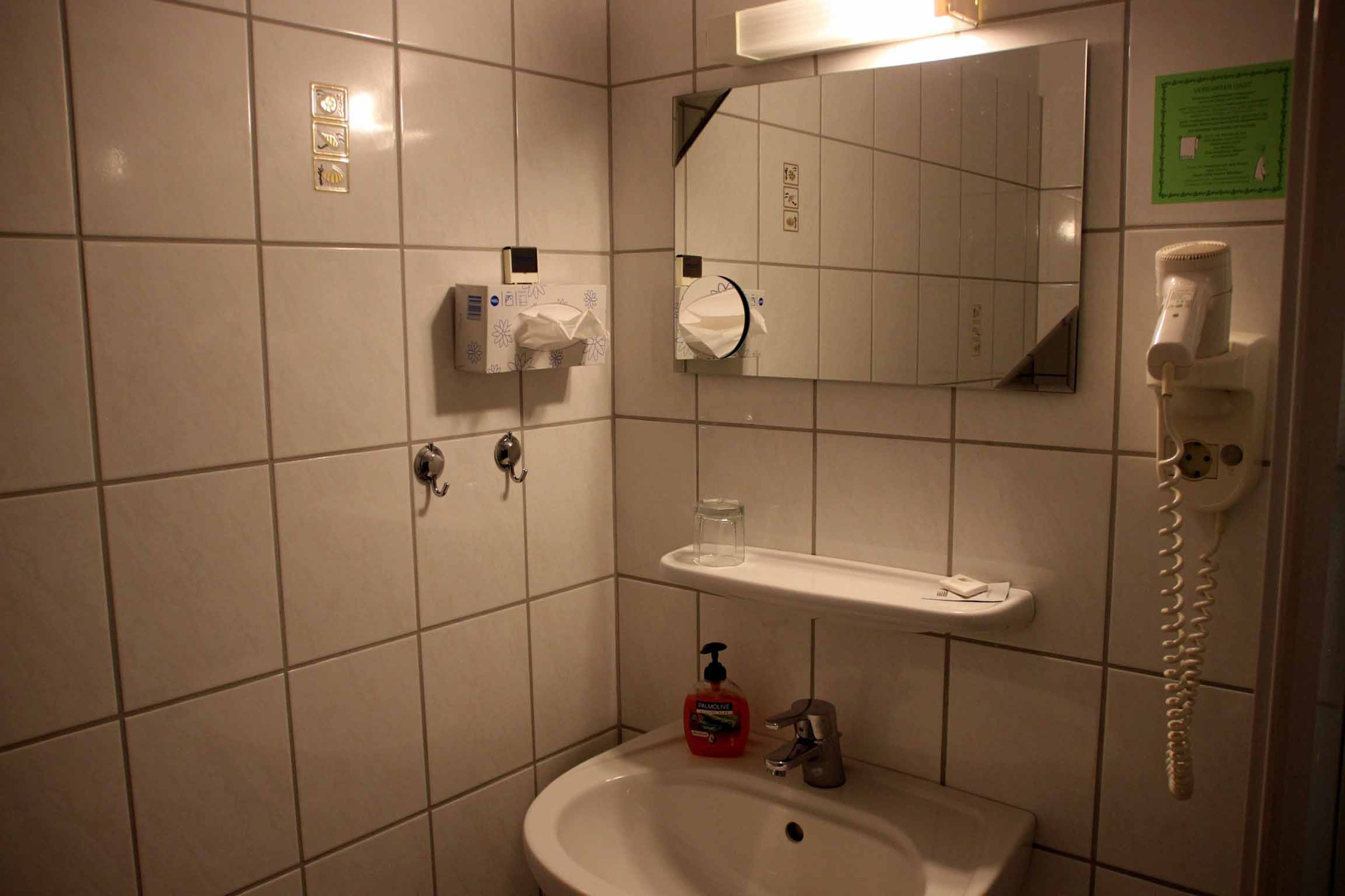 Bagno con lavandino, specchio, dispenser di asciugamani e telefono.