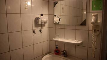 Bagno con lavandino, specchio, dispenser di asciugamani e telefono.