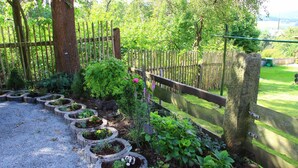 A garden with a gravel path, wooden fence, and various plants. - Hotel Gasthof Zum weissen Lamm (Hohenberg a.d.Eger)