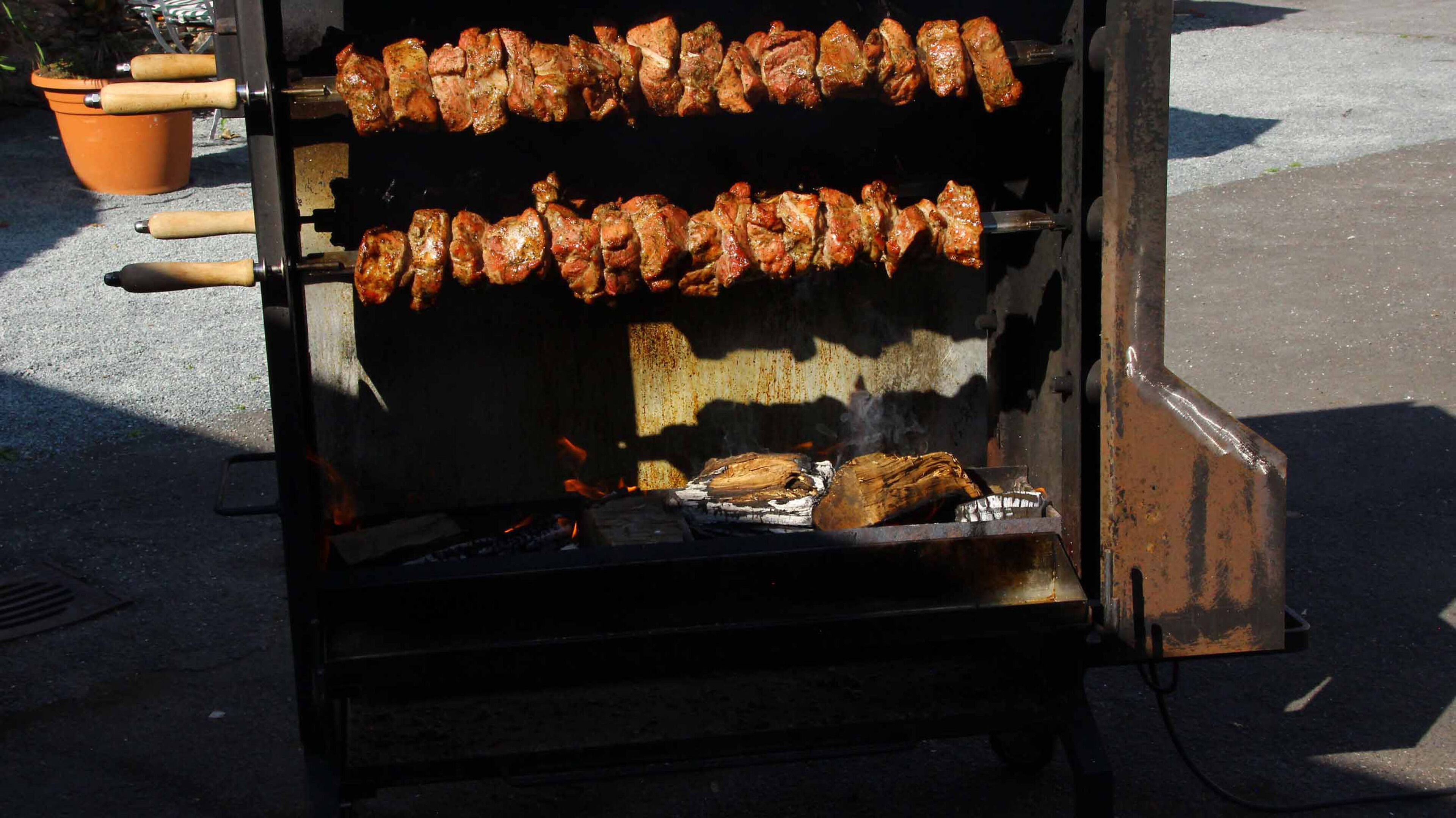 A barbecue grill with skewers of meat being cooked.