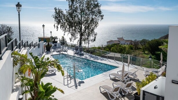 A rooftop pool with lounge chairs, a tree, and a view of the sea. - Apartment with sea and mountain view. HEATED POOL DURING THE WINTER MONTHS  (Nerja)