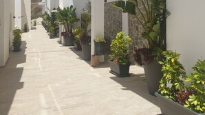 A modern building with a covered walkway lined with potted plants. - Apartment with sea and mountain view. HEATED POOL DURING THE WINTER MONTHS  (Nerja)